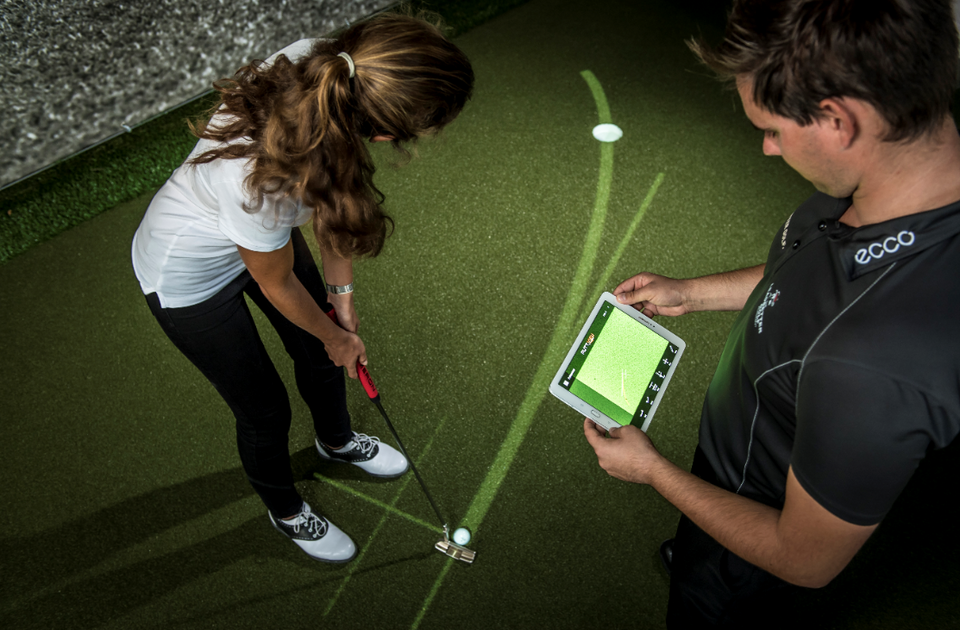 Coach with iPad shows a player how to putt using break lines on the PuttView Canada putting green